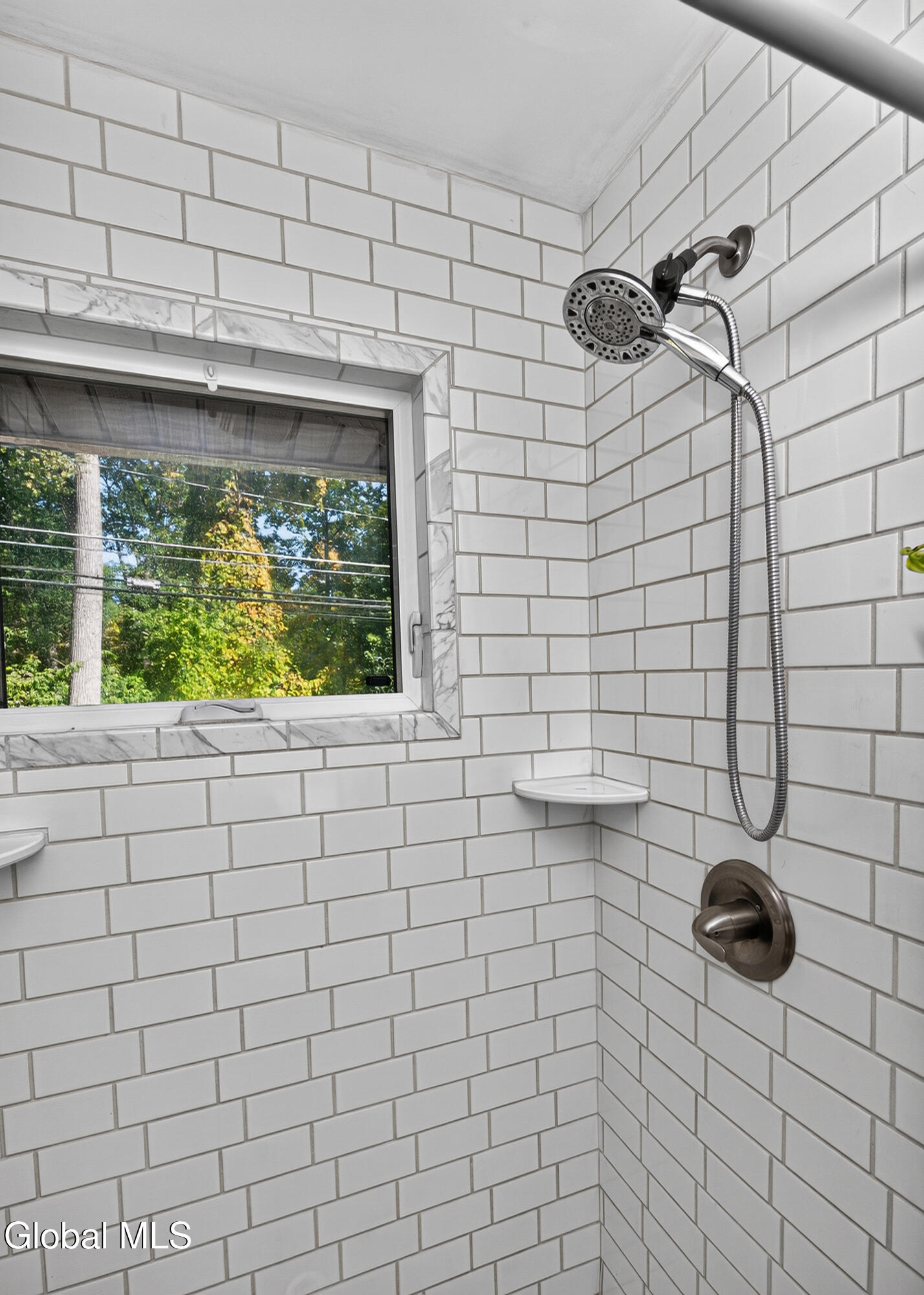 White subway-tile shower with a window and handheld showerhead.