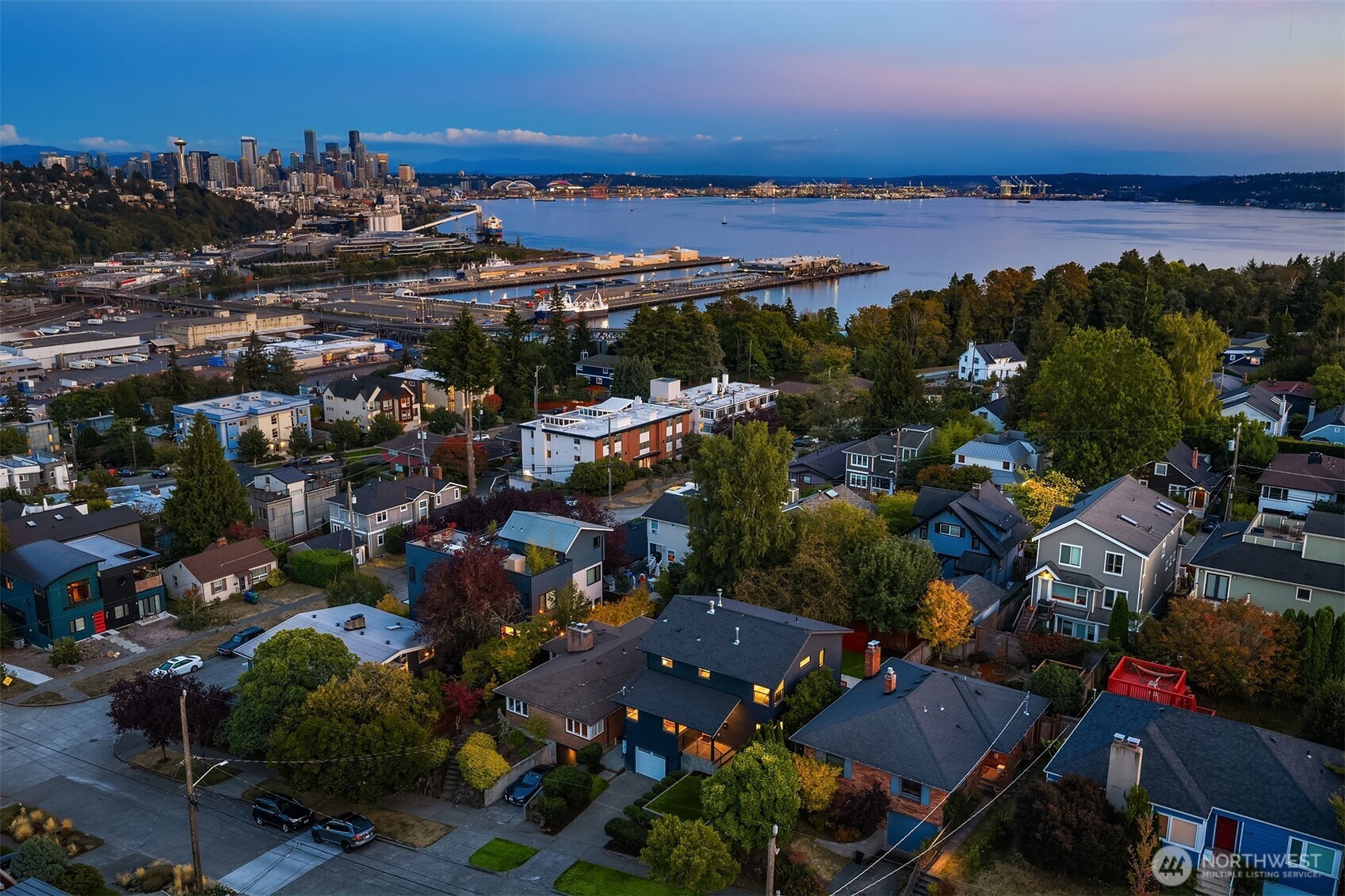 Aerial view of Seattle homes overlooking Elliott Bay, with the downtown skyline and Space Needle in the distance.