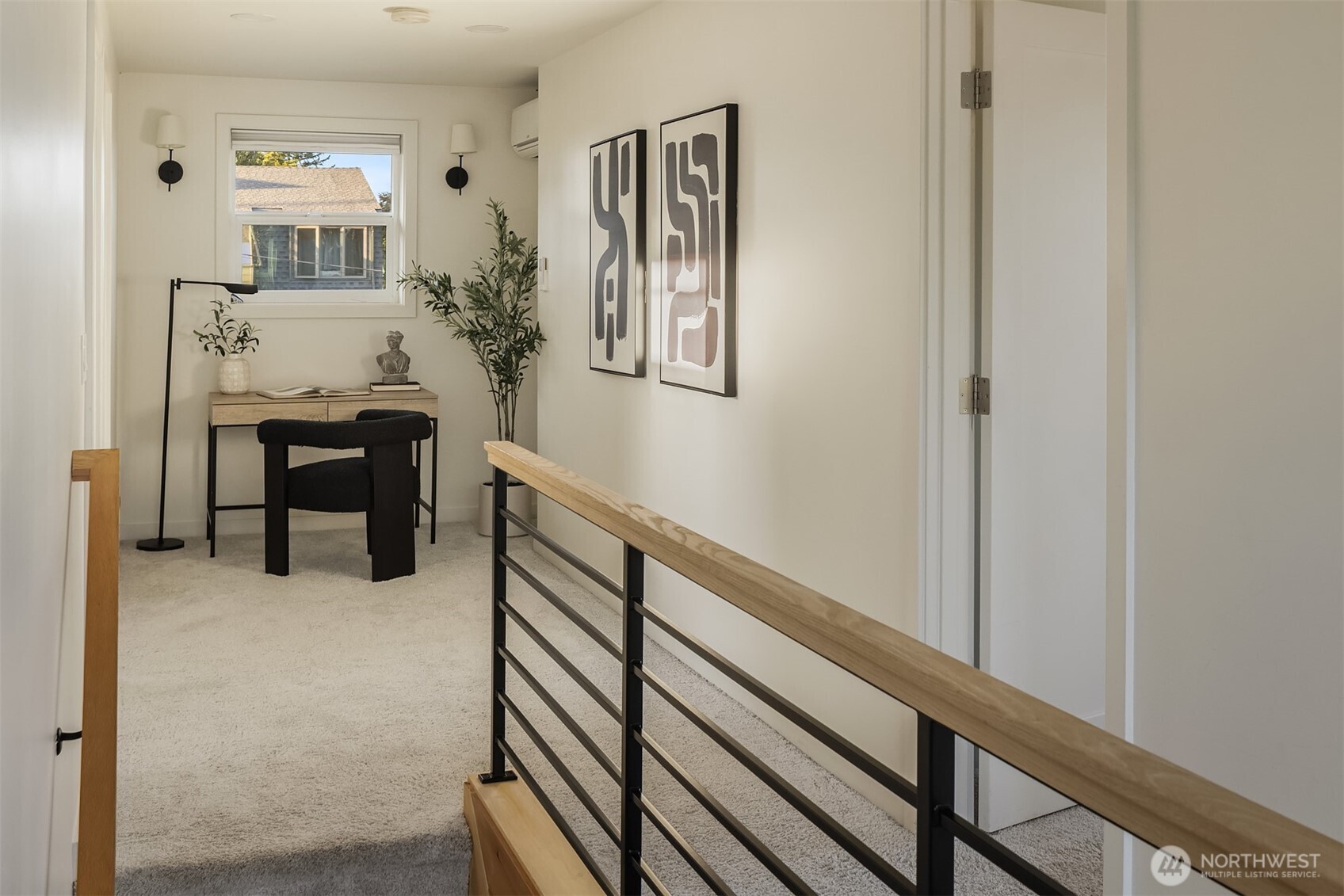 Upstairs landing with a desk beneath a window and a wood-topped black railing.