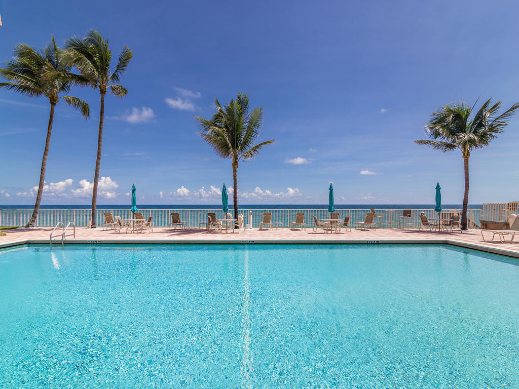Oceanfront swimming pool with palm trees and lounge chairs along the deck.