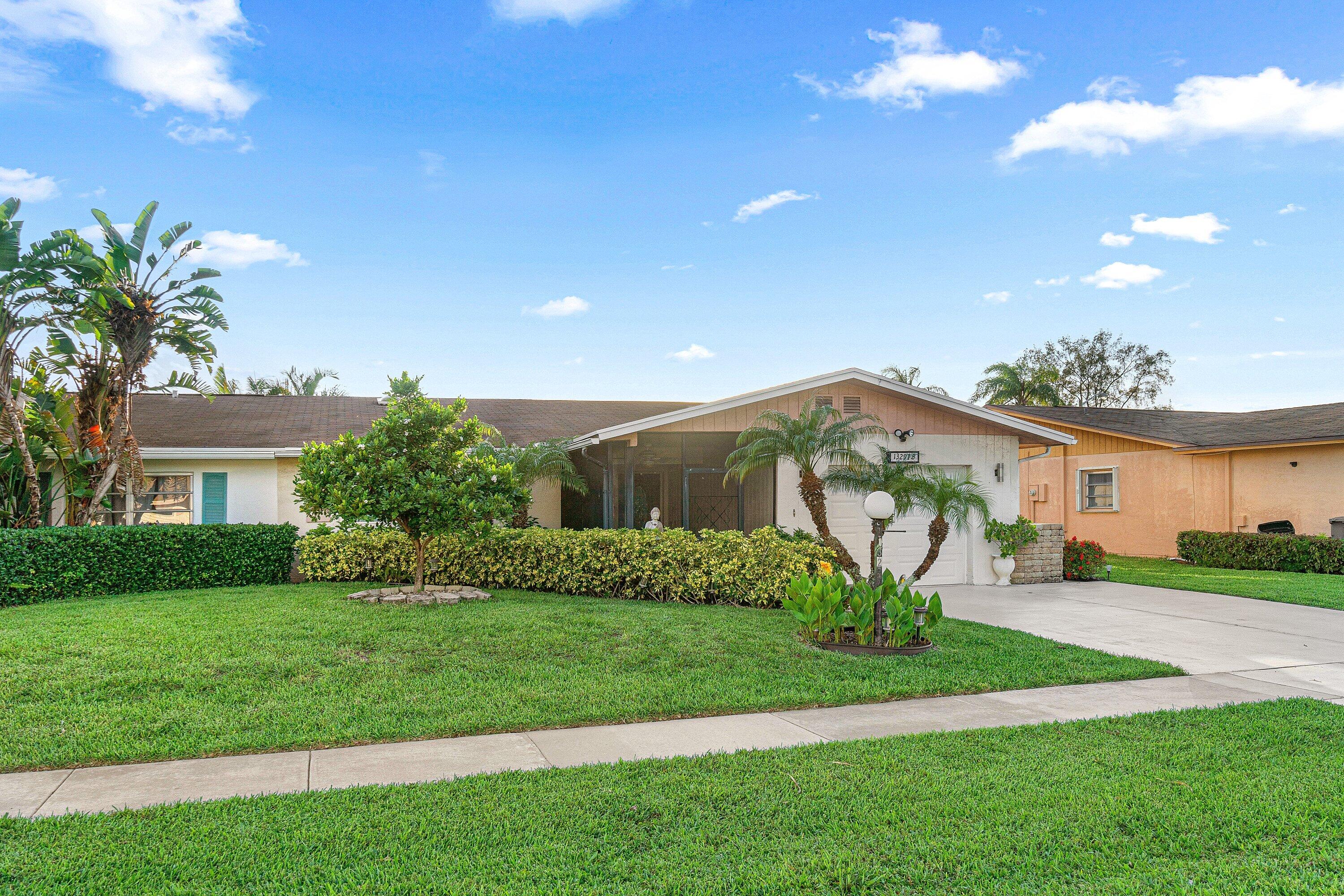 Single-story home with a screened porch, palm trees, and a broad green lawn.
