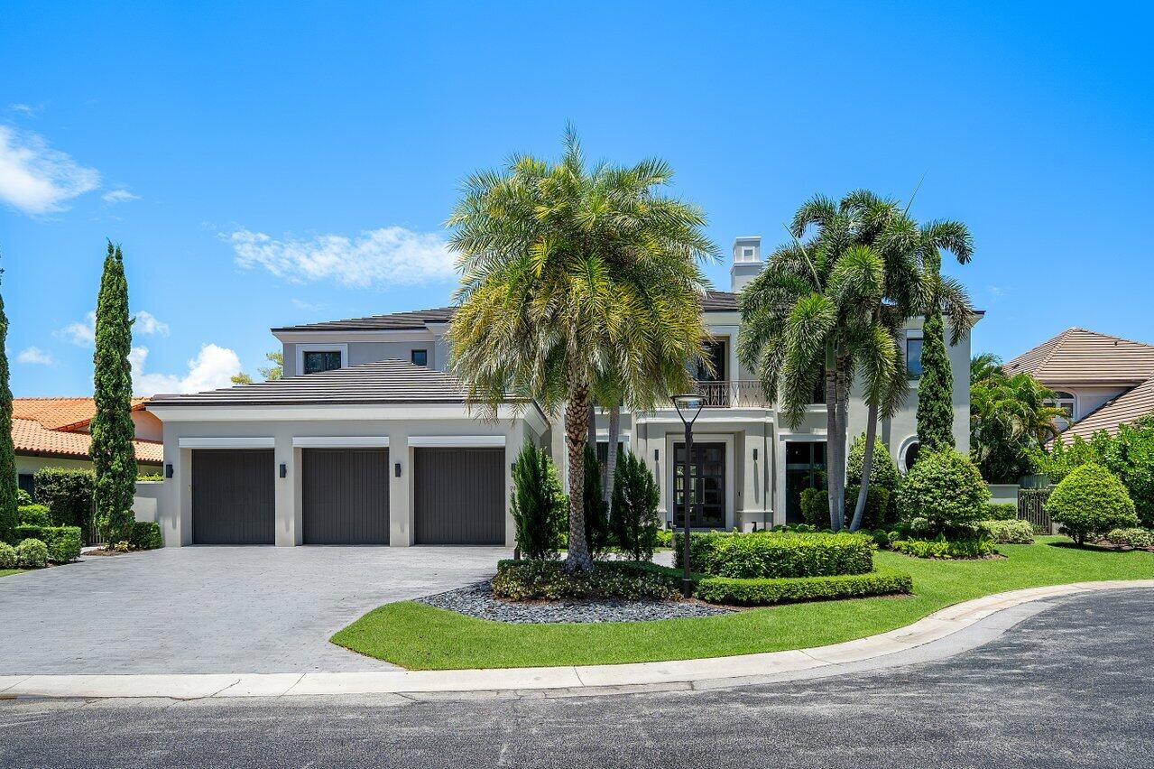 Modern two-story home with a three-car garage, palm trees, and manicured lawn.
