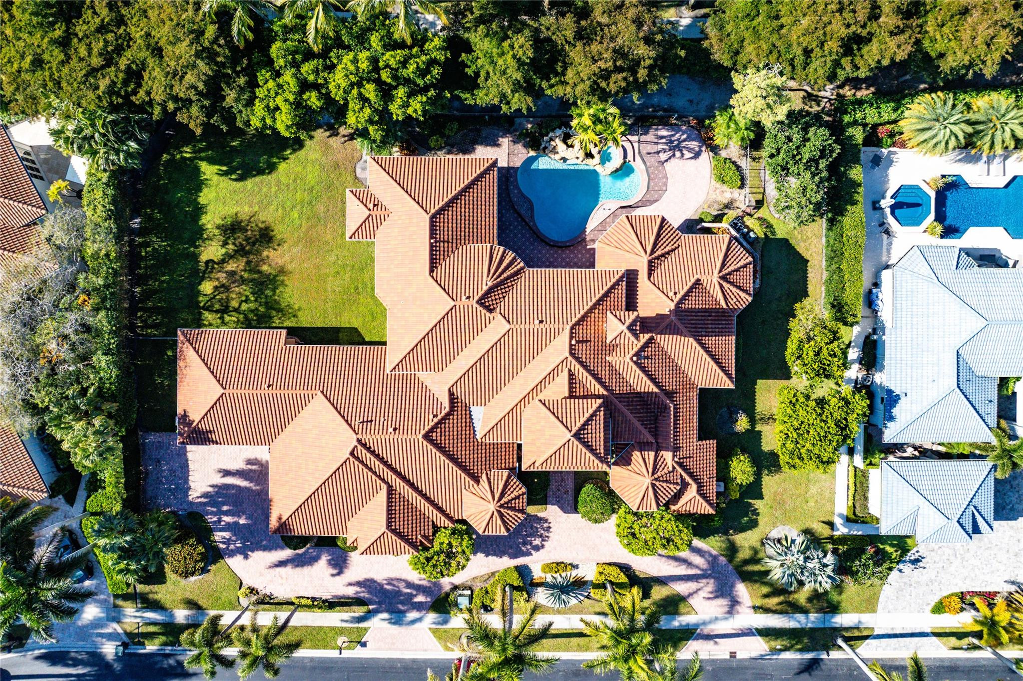 Aerial view of a terracotta-roofed home with a backyard pool and circular driveway.