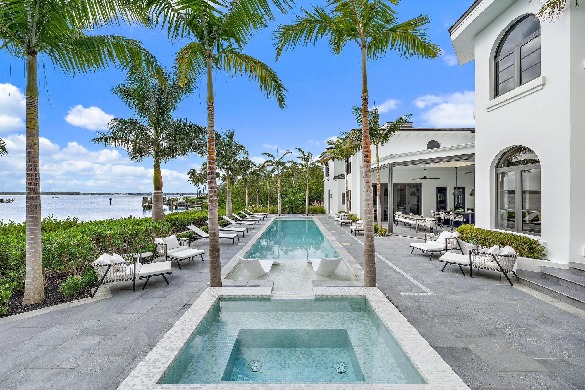 Waterfront home with a palm-lined pool, spa, and patio overlooking the bay.