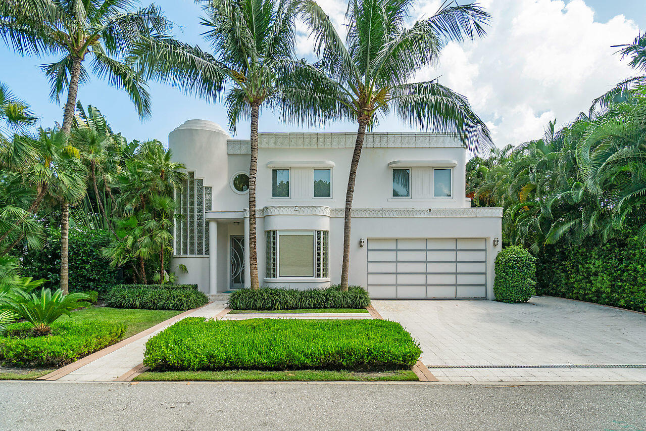 Modern white two-story home with a rounded facade, wide garage, and palm-lined driveway.