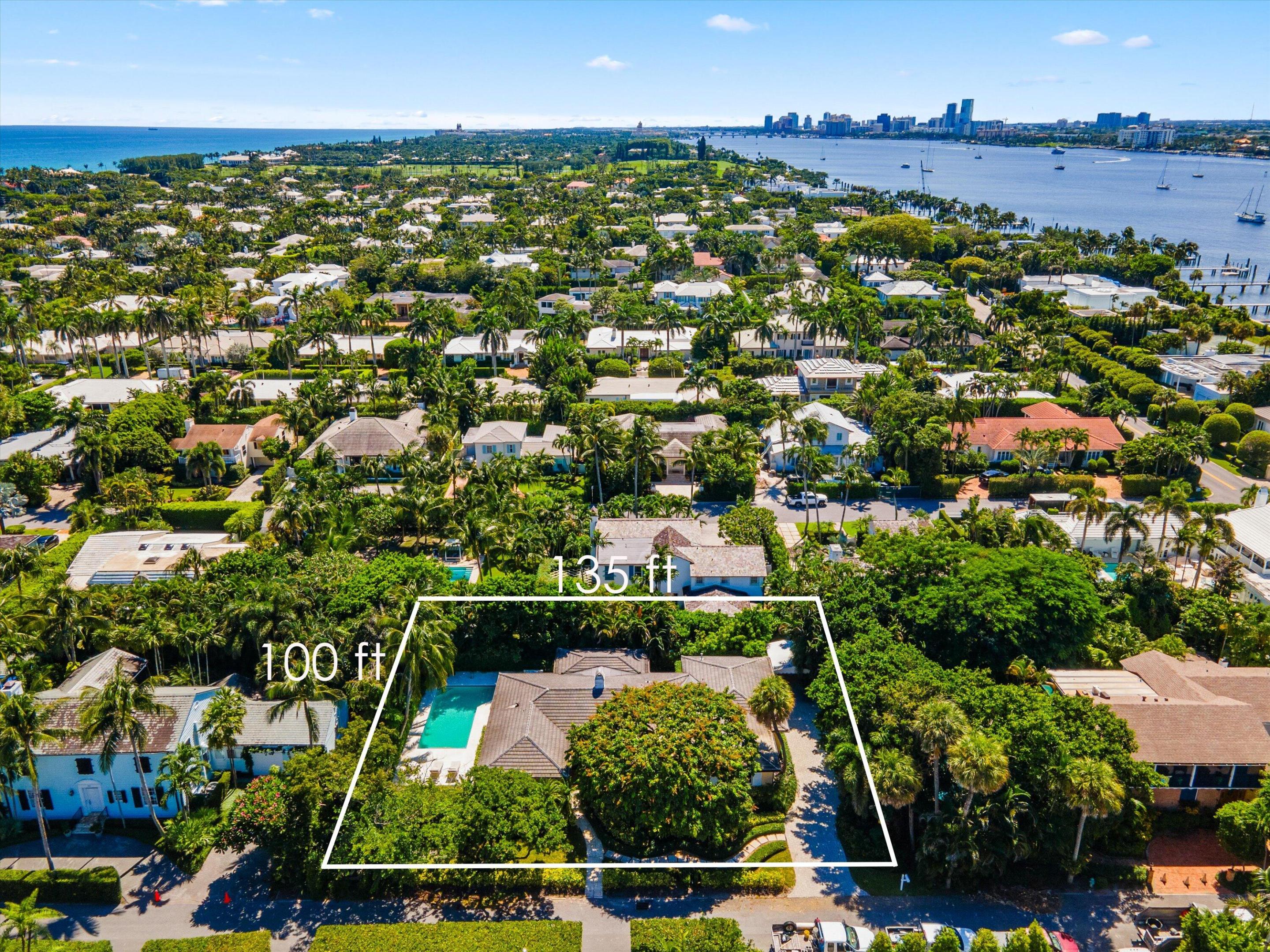 Aerial view of a palm-filled property with a house and pool, outlined with 135-foot and 100-foot dimensions.