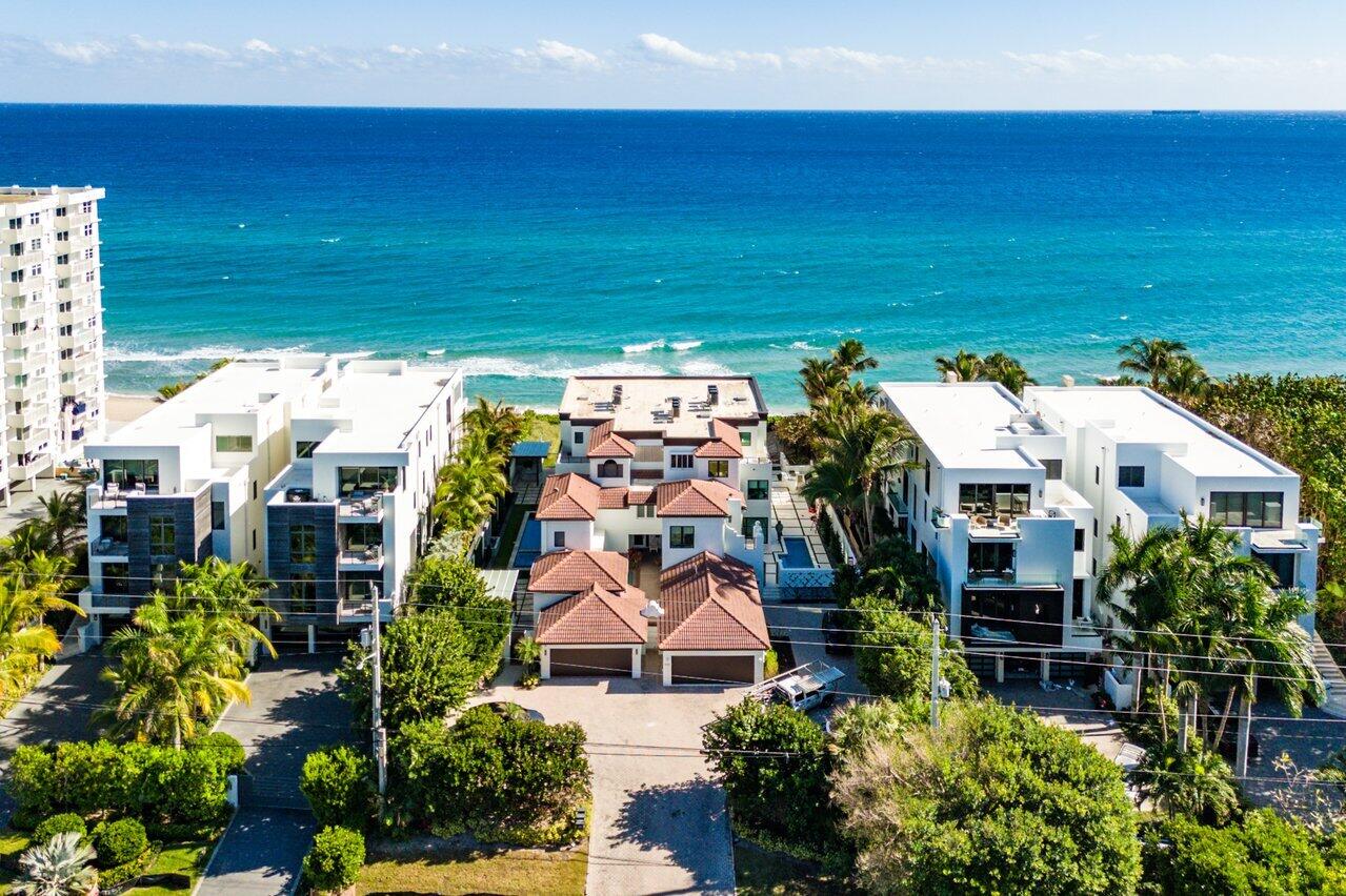 Aerial view of a beachfront home with terracotta roofs, neighboring modern houses, and the Atlantic Ocean.