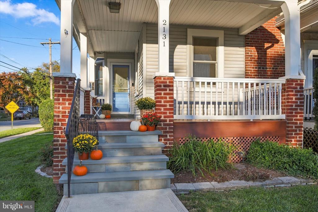 Front porch with brick pillars, white railing, and pumpkin-and-flower decorations on the steps.