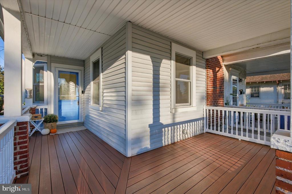 Covered front porch with gray siding, a blue door, and wide composite decking.