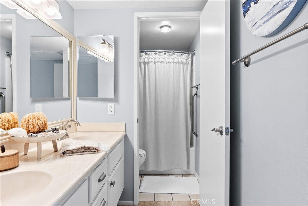 Bathroom with a long vanity, mirrored medicine cabinets, and a curtained shower.