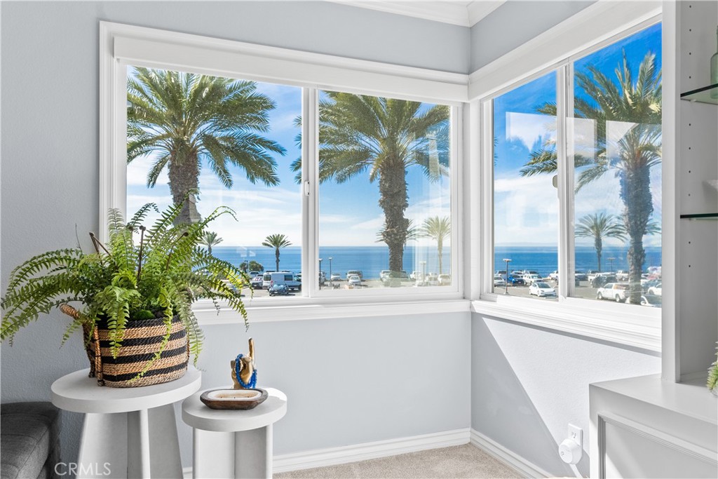 Bright room with wraparound windows overlooking the ocean and palm trees.