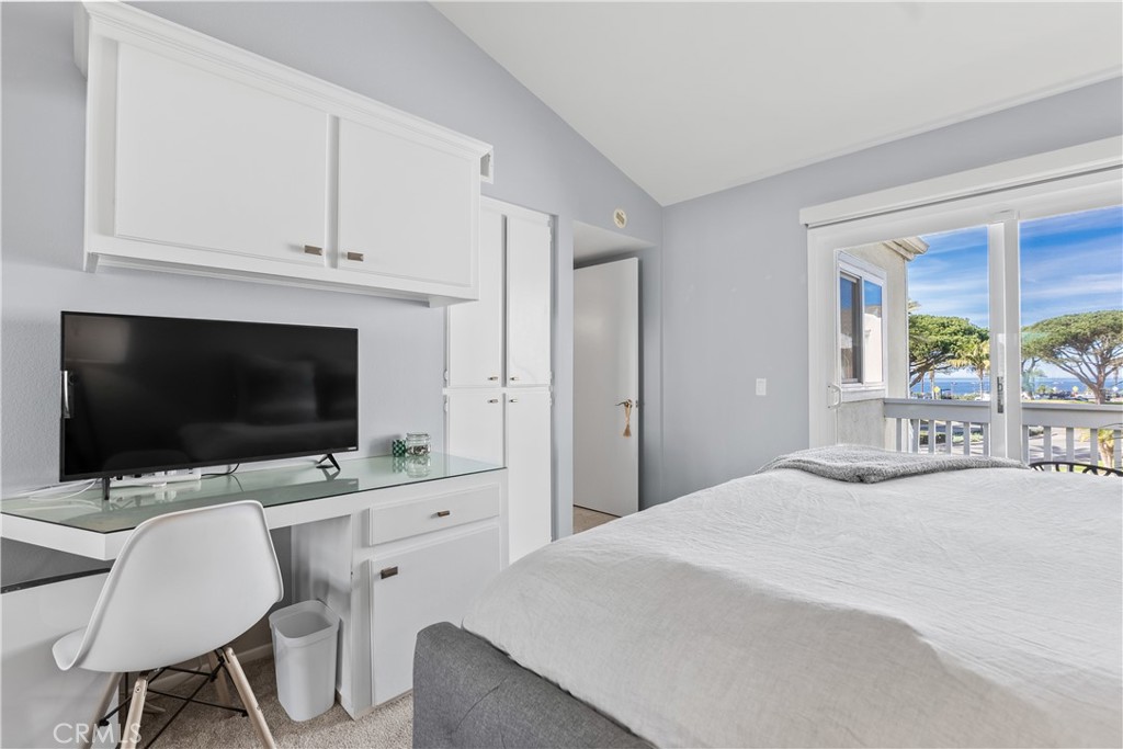 Bedroom with built-in desk and cabinets, and ocean views through sliding glass doors.