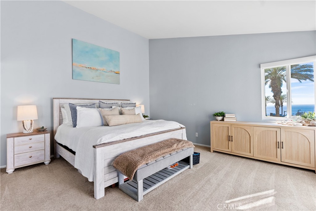 Bedroom with a light wood bed and ocean view through a window.