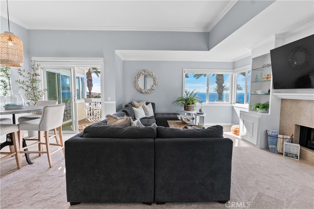 Living room with a dark sectional, fireplace, and ocean views through large windows.
