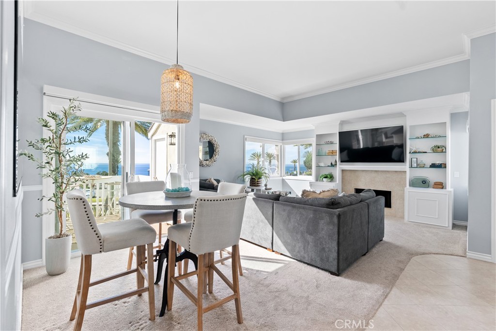 Living and dining area with a fireplace, built-in shelves, and ocean views through large windows.