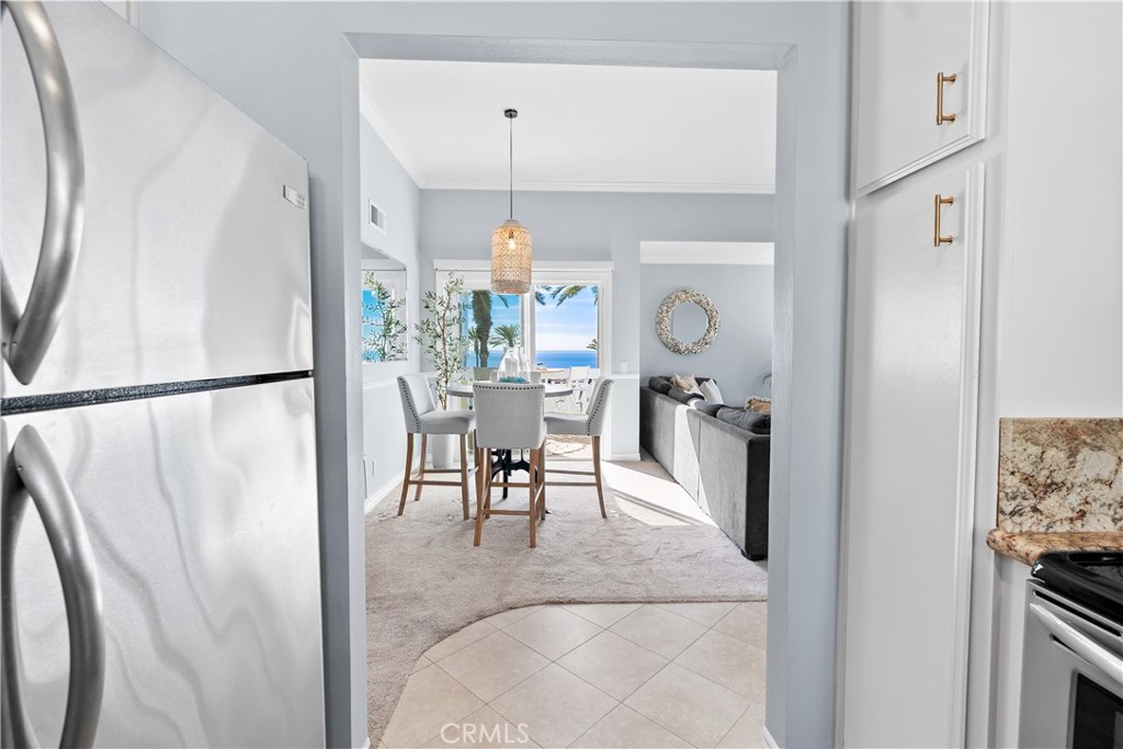 Kitchen opening to a dining area, with stainless appliances and ocean views through the windows.