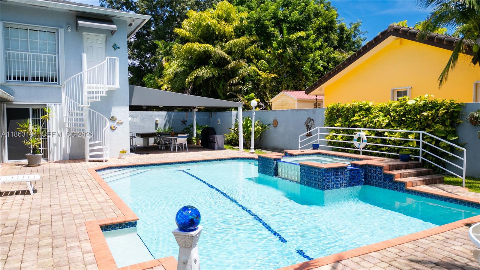 Backyard swimming pool with raised spa, brick paver deck, and covered outdoor dining area.