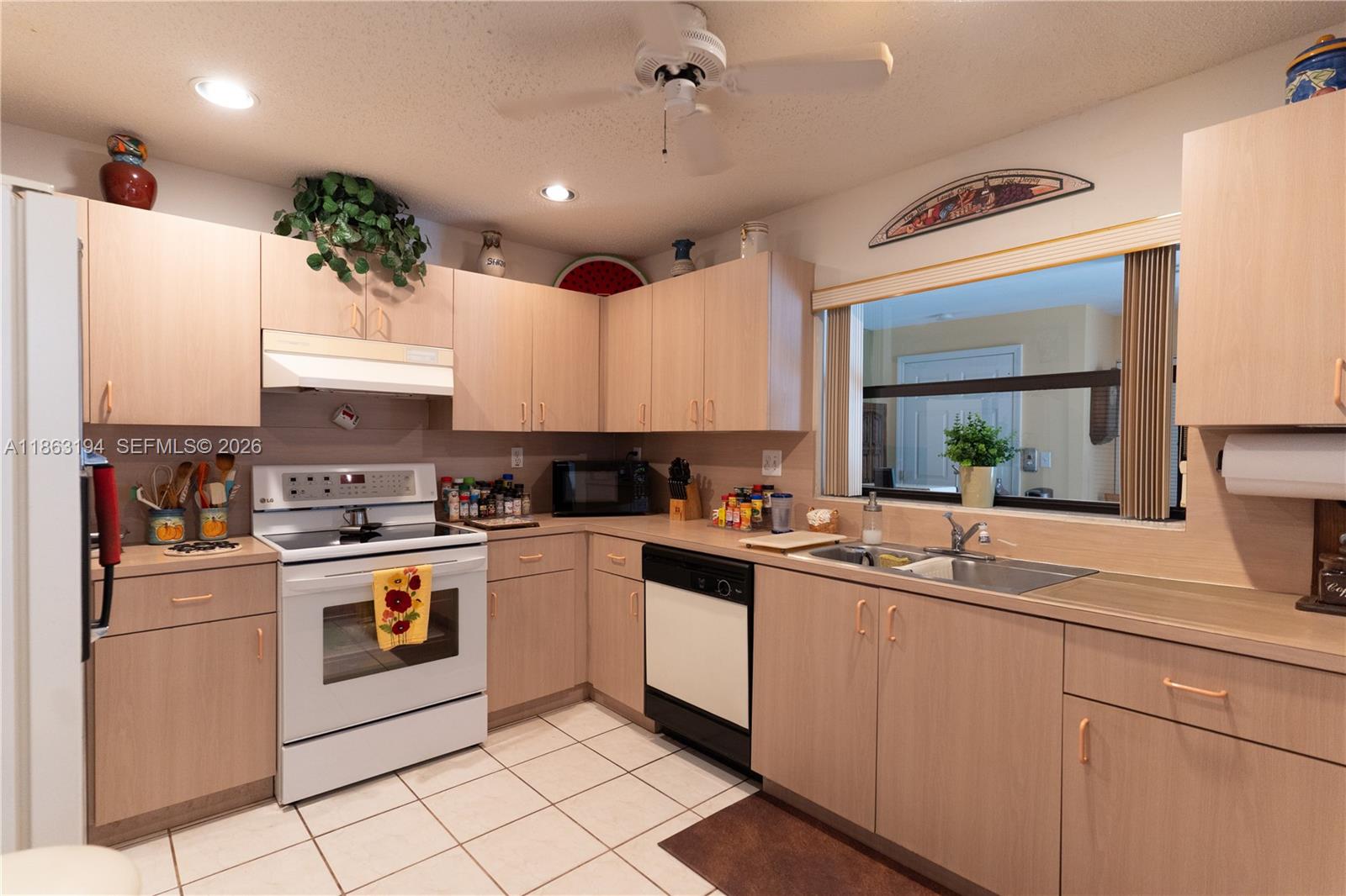 Kitchen with light wood cabinets, white range, double-basin sink, and pass-through window.