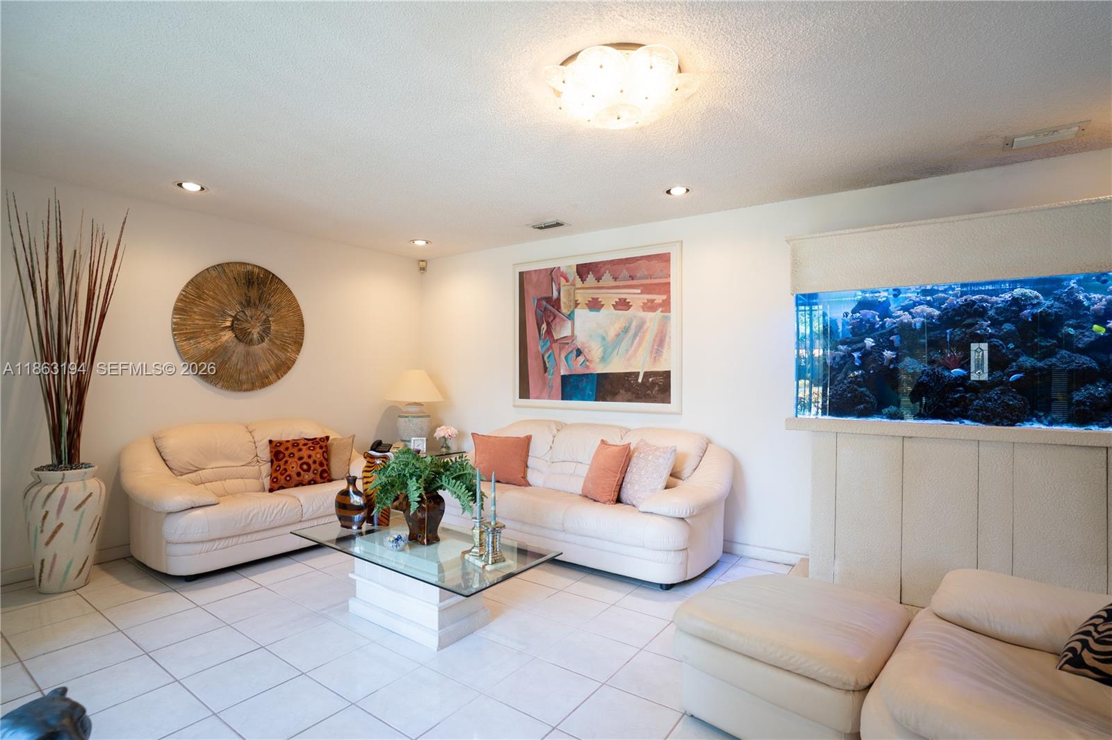 Living room with cream sectional sofas and a large built-in aquarium.