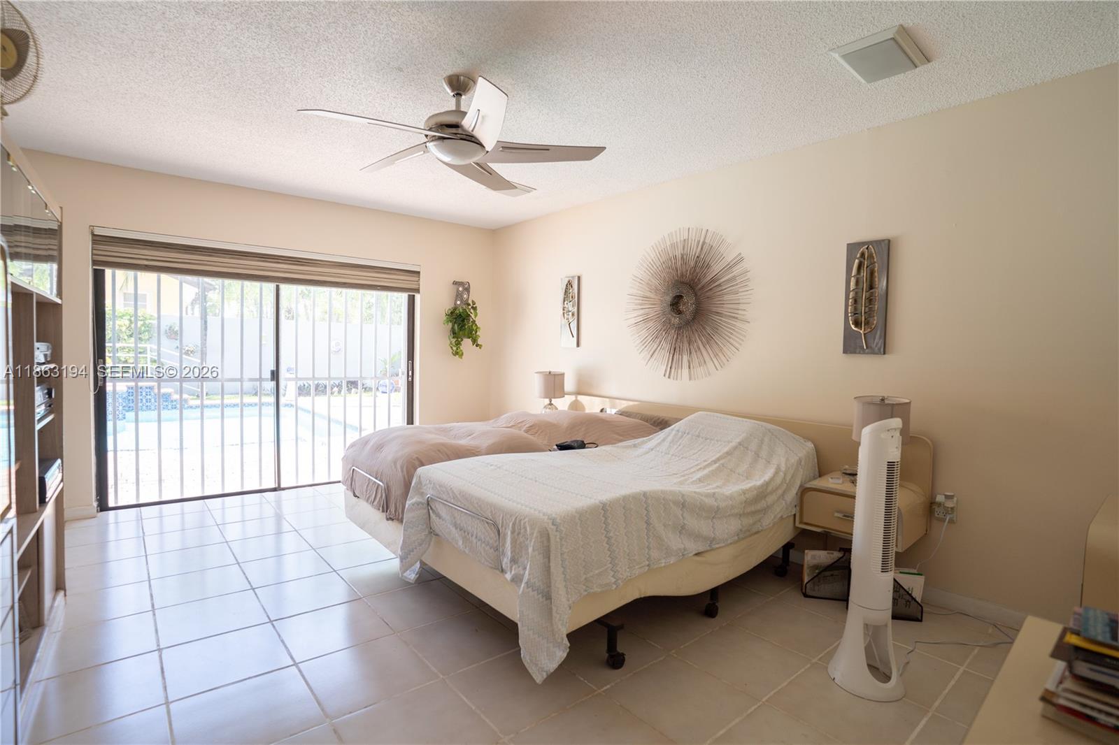 Bedroom with two beds and sliding glass doors overlooking a pool.