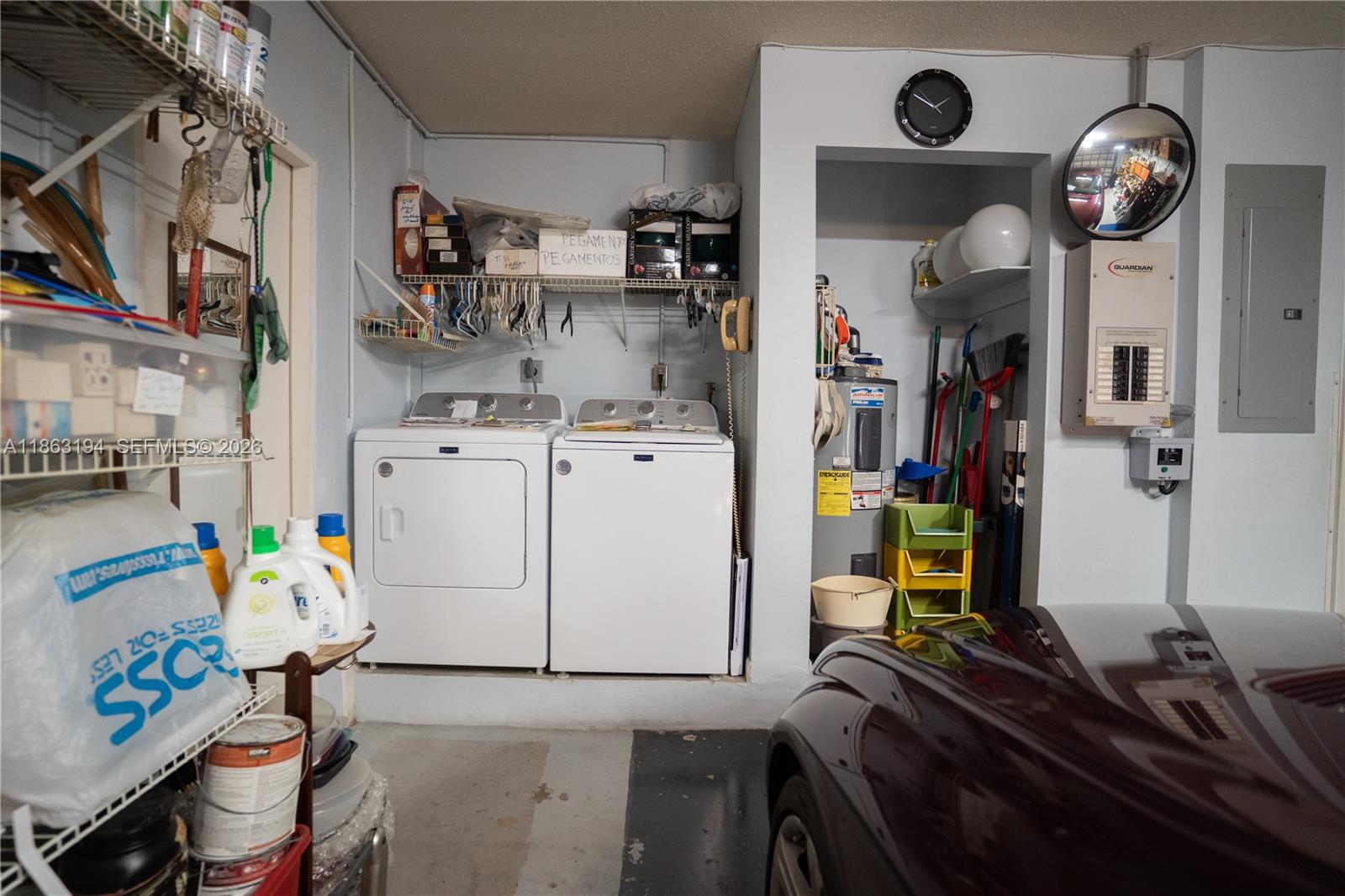 Garage laundry area with a washer and dryer, storage shelves, and part of a parked car.
