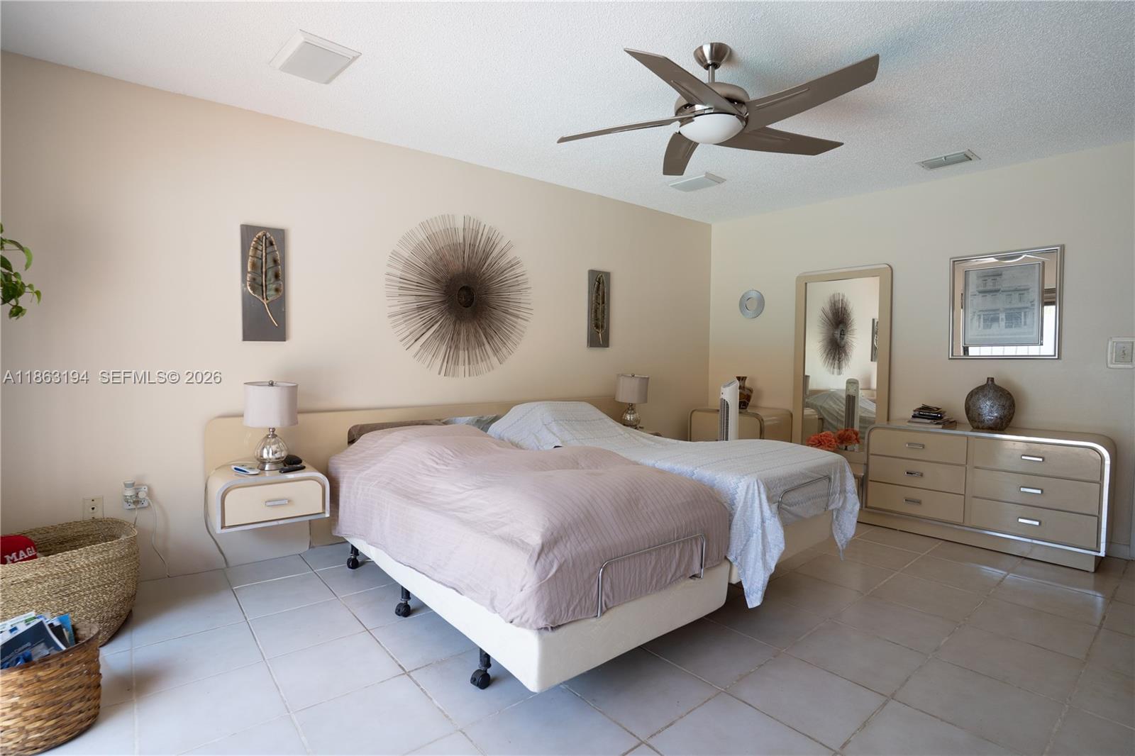 Furnished bedroom with two beds, a ceiling fan, tiled floors, and metallic wall art.