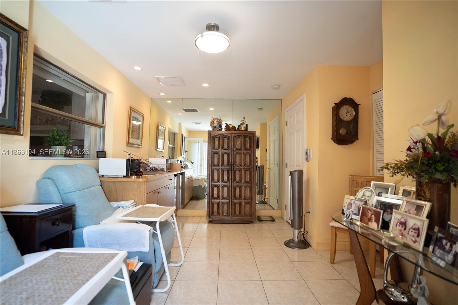 Furnished interior with pale blue seating, mirrored wall, and carved wooden cabinet.