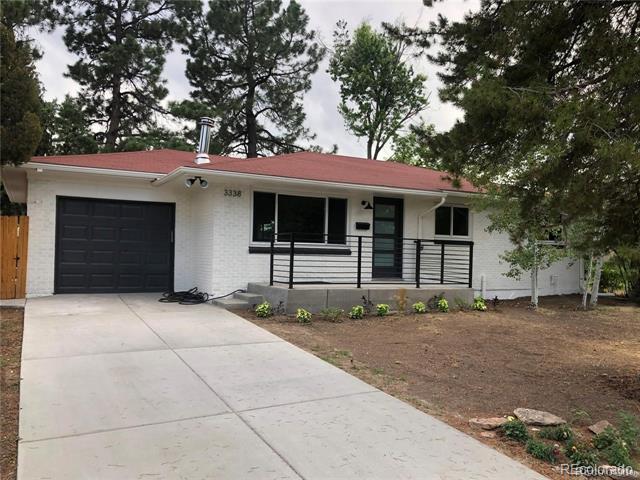 White brick single-story house with a red roof, black garage door, and broad concrete driveway.