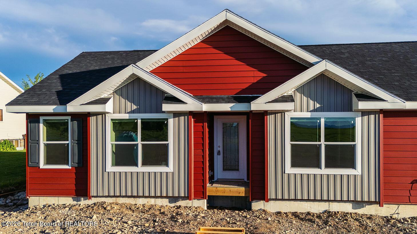 Red and gray single-story house with white trim, multiple front windows, and a recessed entry.