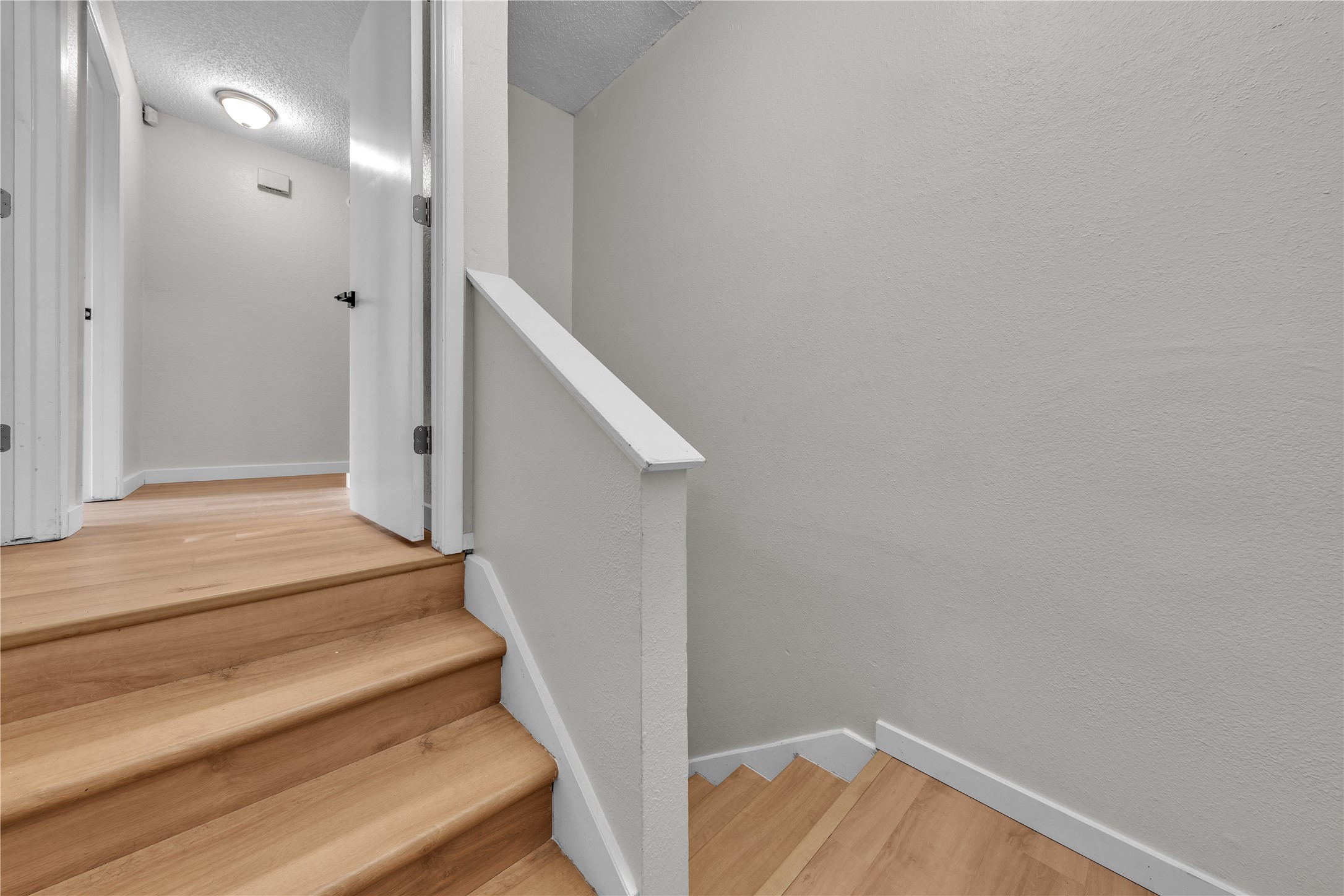 Light wood staircase with an upper landing and open doorway.