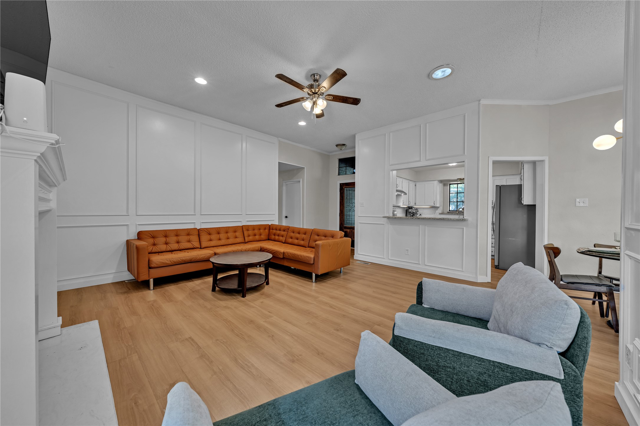 Furnished living room with white paneled walls, wood floors, and a rust-colored sectional sofa.