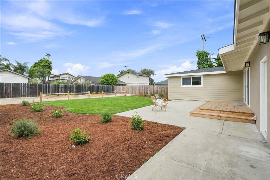 Backyard patio with lawn, fenced landscaping, and a small raised wood deck.