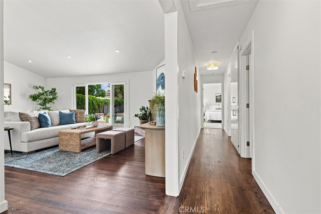 Bright living room with sliding glass doors beside a long hallway and hardwood floors.