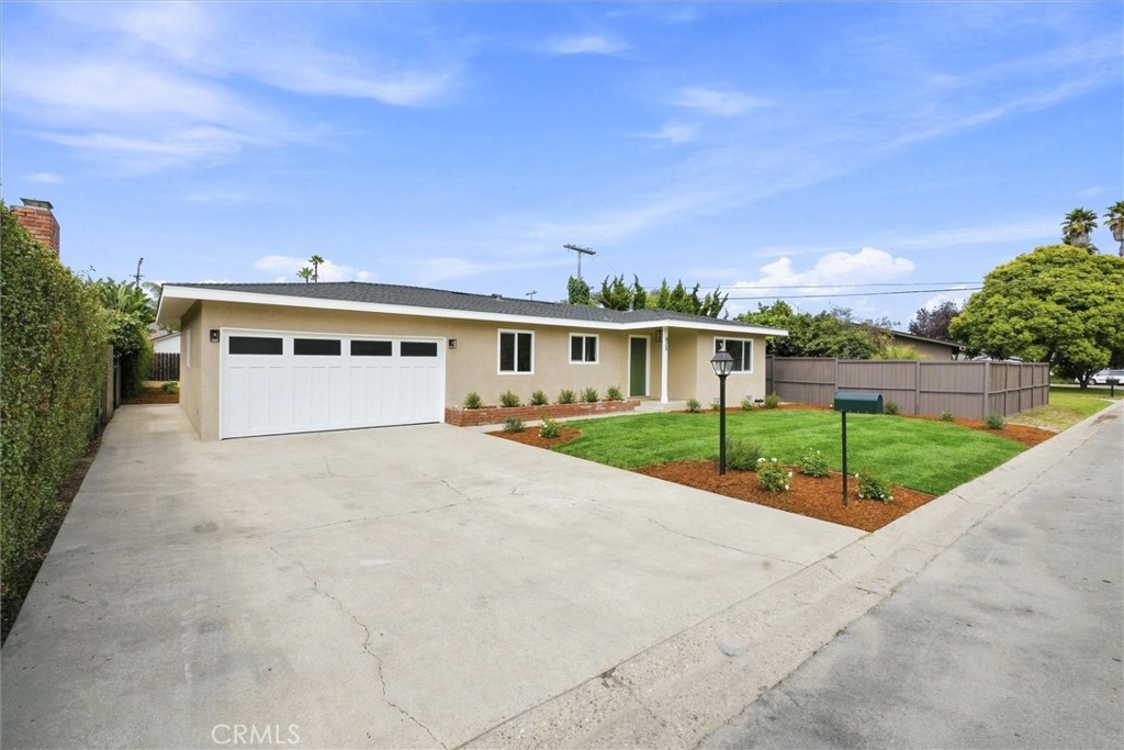 Single-story home with a wide driveway, white double garage door, and landscaped front lawn.