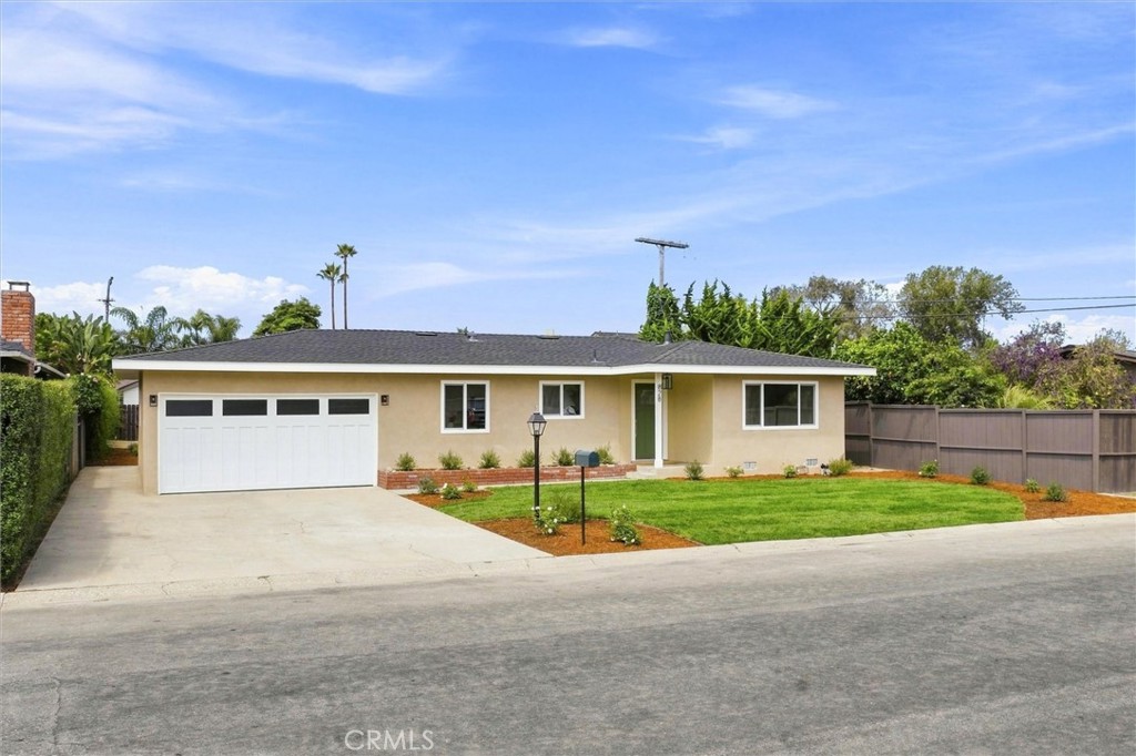 Single-story beige home with a two-car garage, broad driveway, and landscaped front lawn.