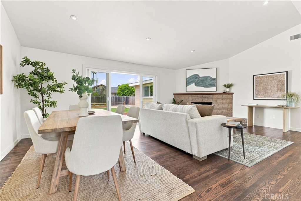 Open-plan living and dining room with a brick fireplace and sliding glass doors to the yard.