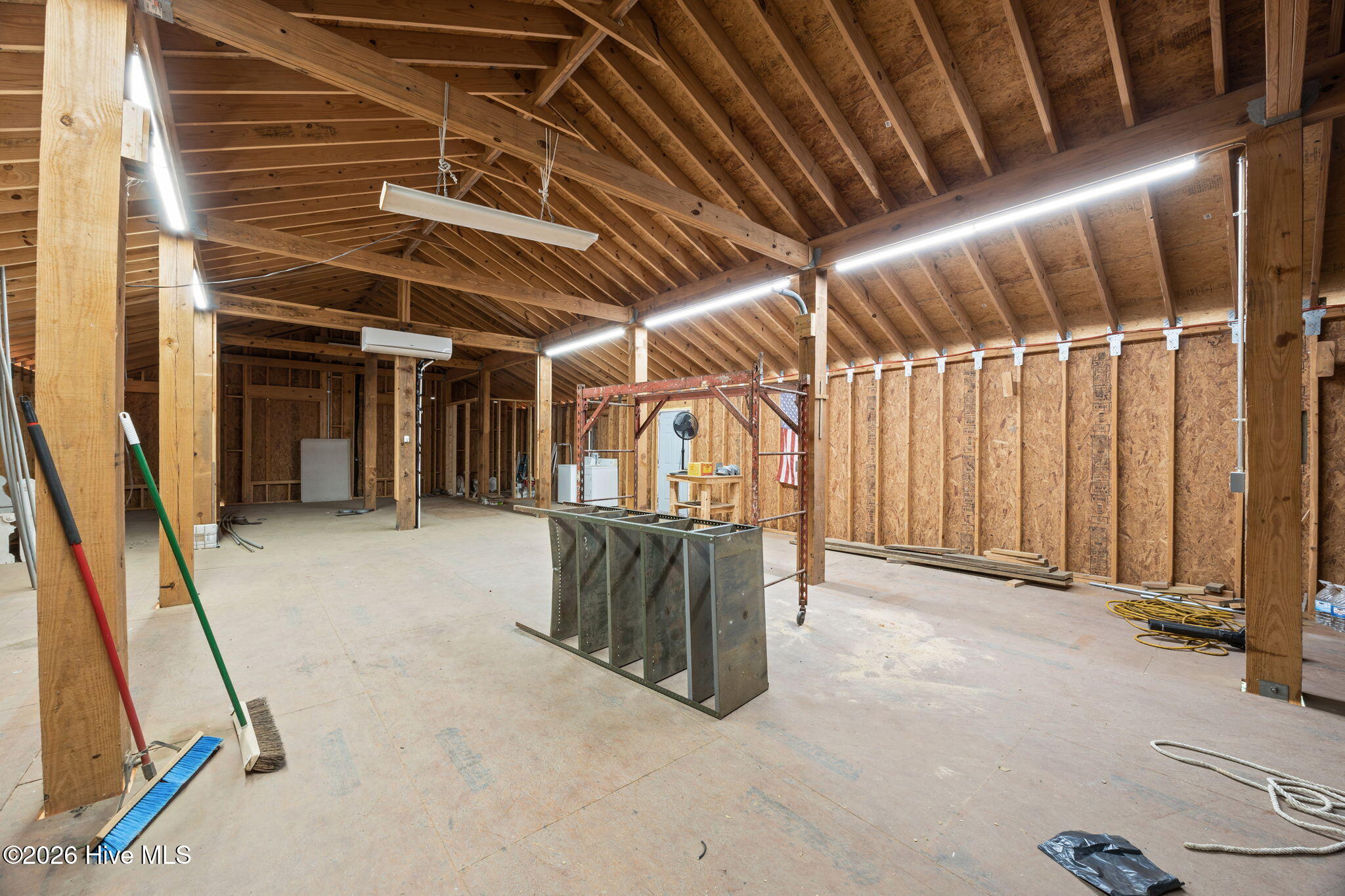 Unfinished timber-framed outbuilding interior with exposed roof trusses and construction materials.