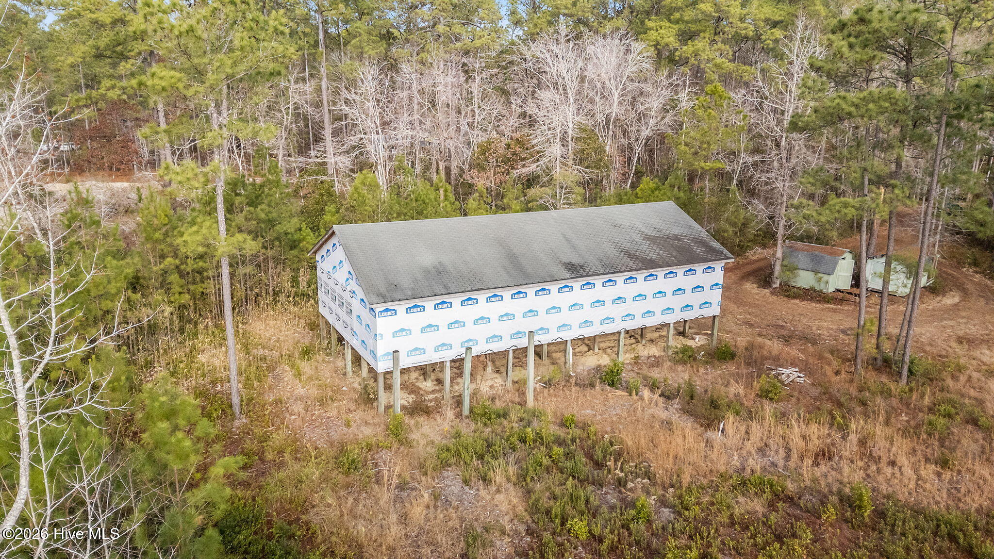 Aerial view of a raised building under construction, wrapped in Lowe’s house wrap and surrounded by woods.