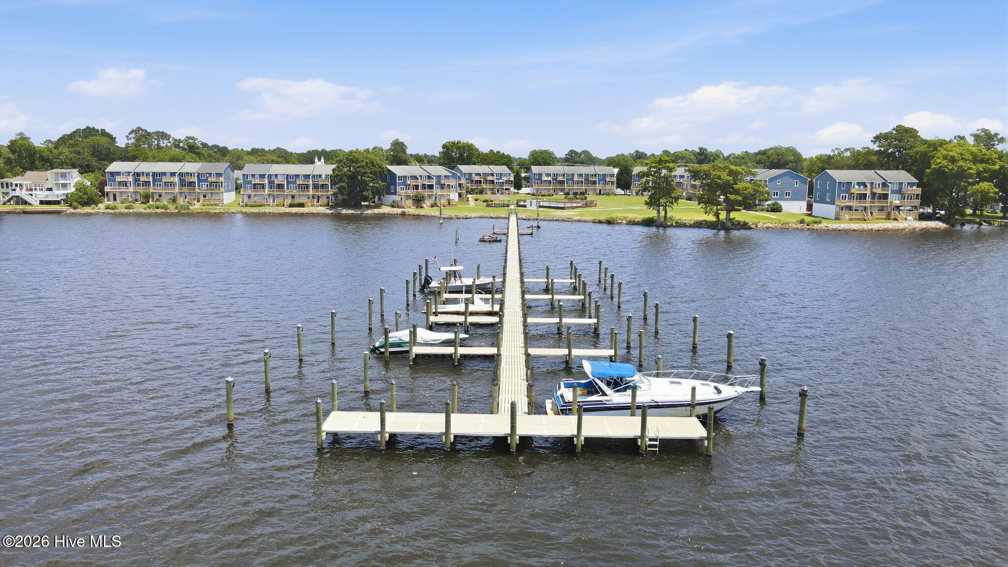 Waterfront townhouse community with a long pier, boat slips, and boats on the water.