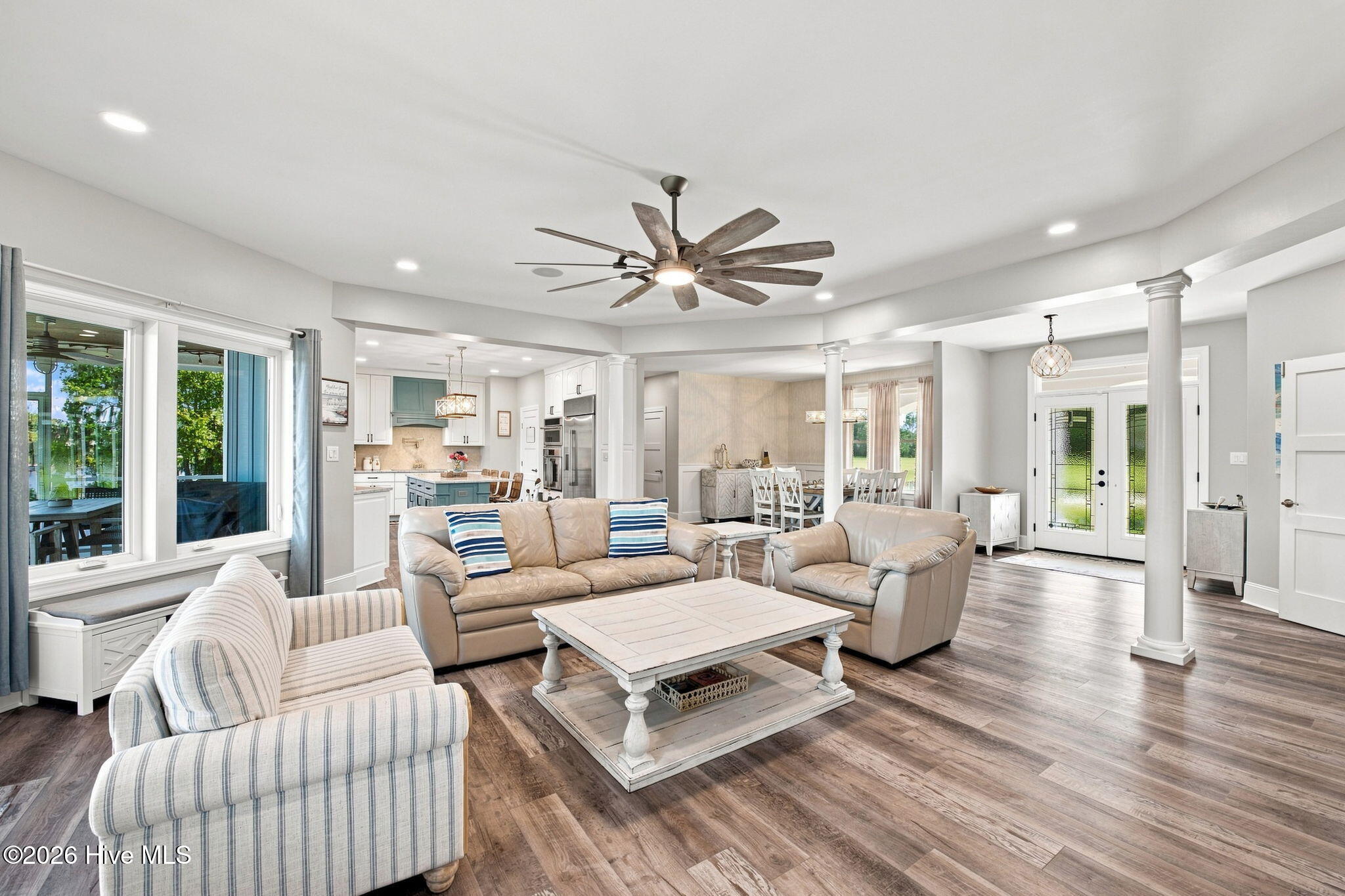 Open-plan living room with beige seating, a white coffee table, and views into the kitchen and dining area.