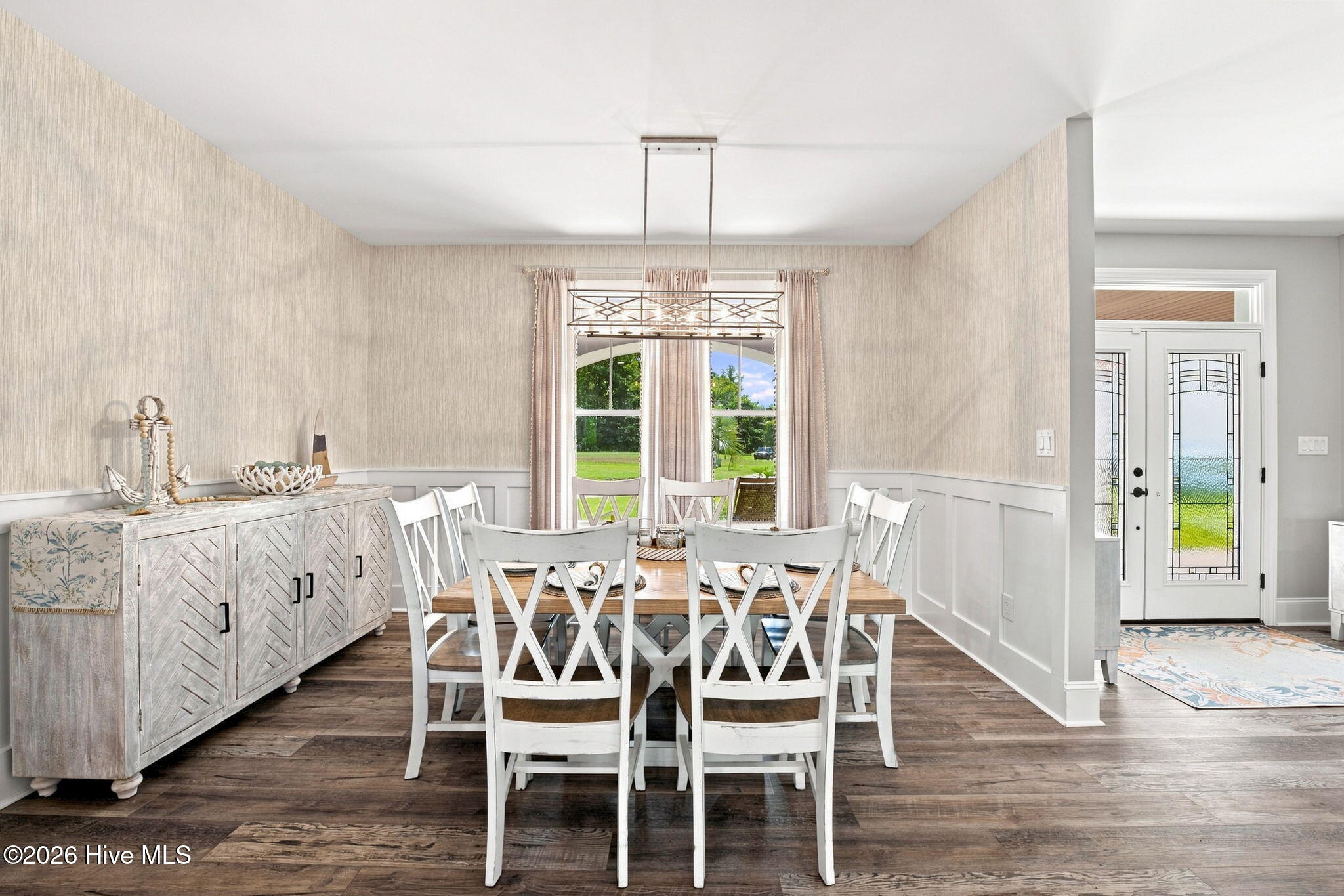 Dining room with white X-back chairs, a wood table, and a distressed white sideboard.