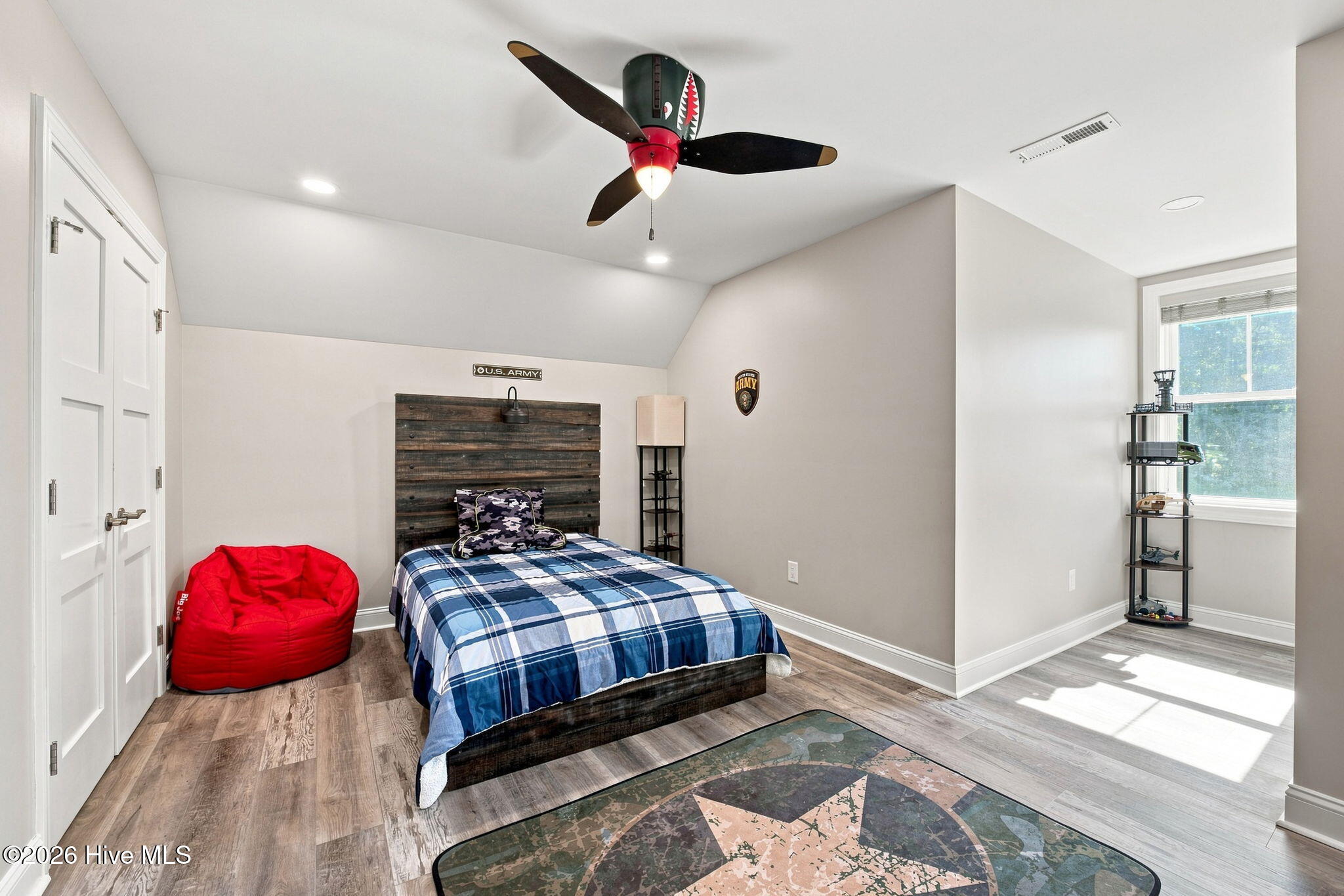 Bedroom with blue plaid bedding, a red beanbag chair, and Army-themed decor.
