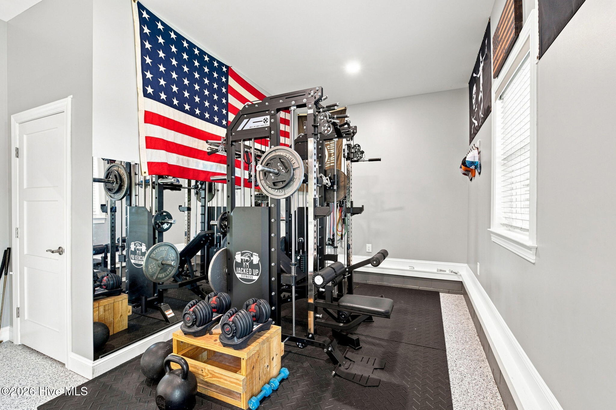 Home gym with cable machine, free weights, mirrored wall, and American flag.