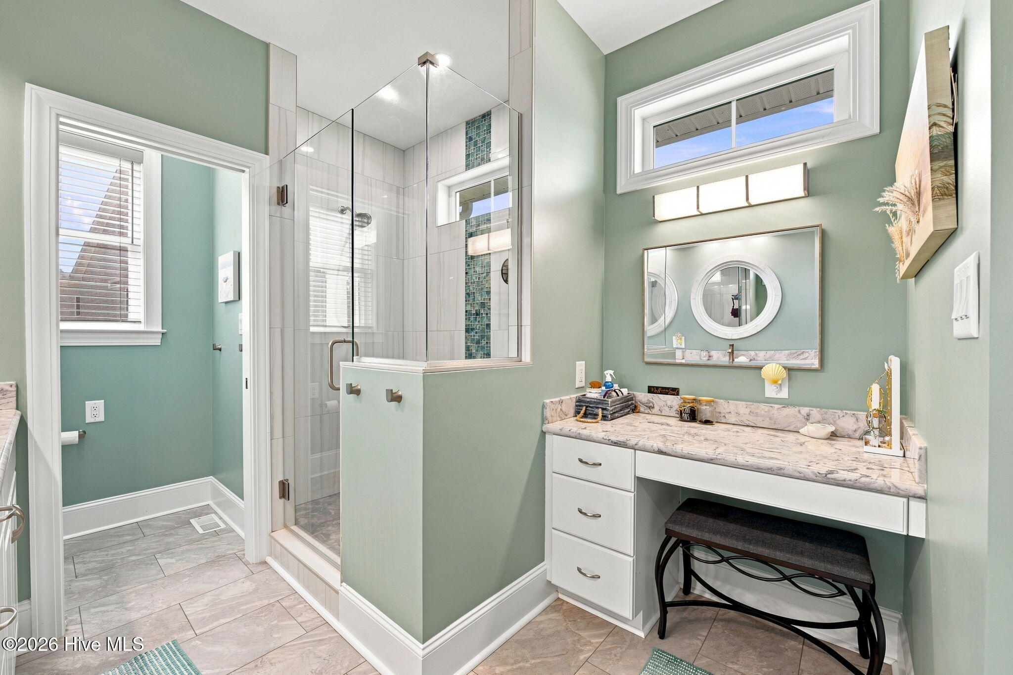 Bathroom with sage-green walls, a glass shower, and a white vanity with a marble-pattern countertop.