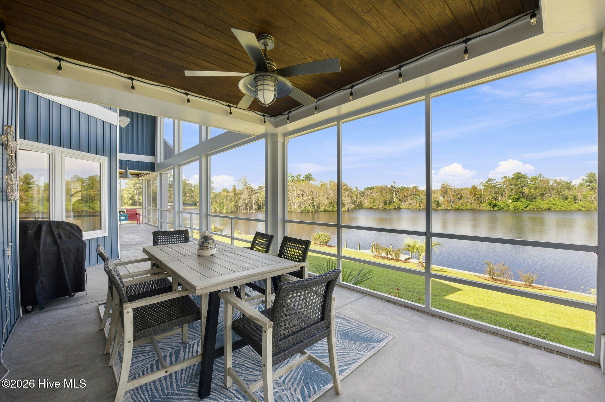 Screened porch dining area with a wood ceiling and wide water views.