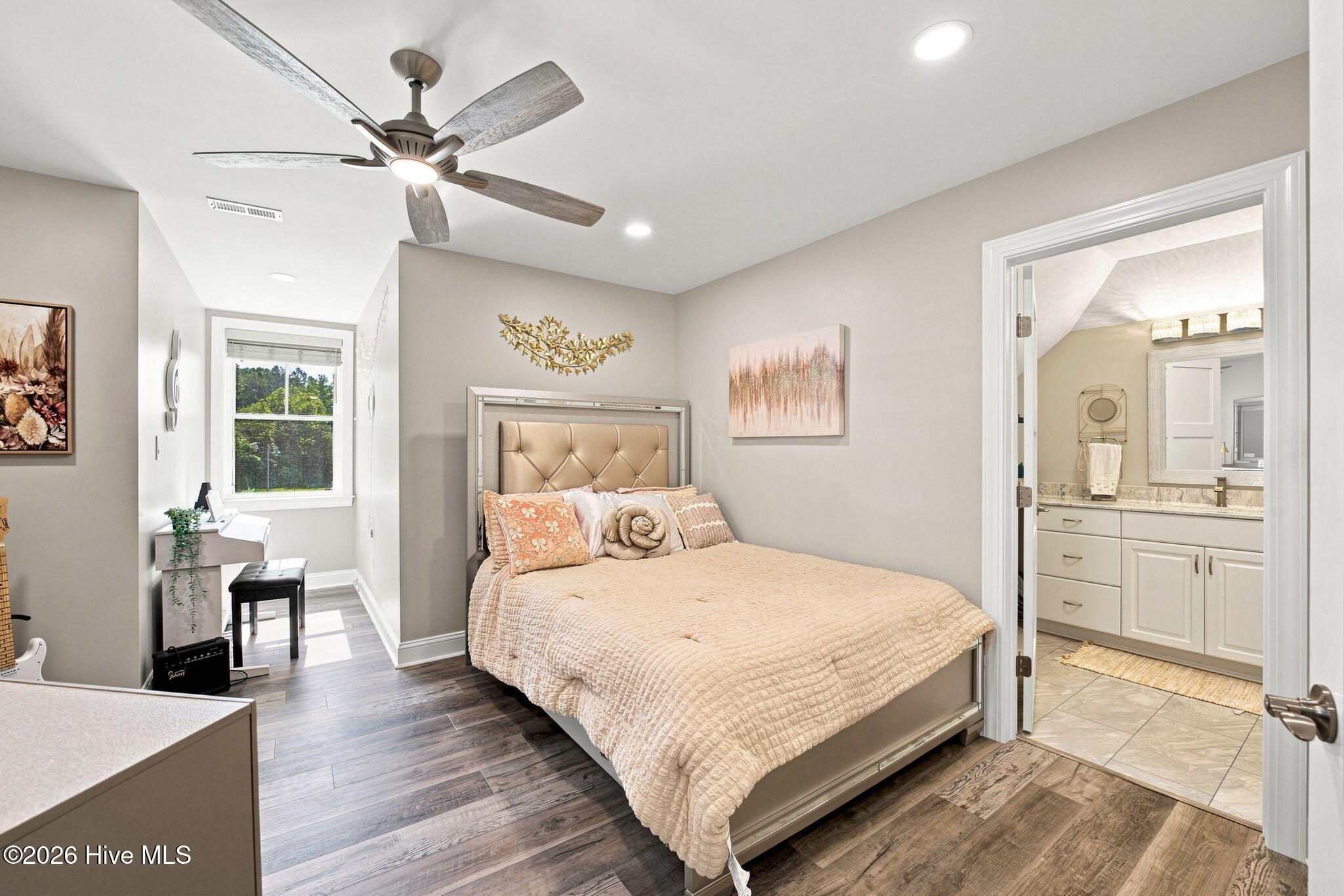 Bedroom with a tufted bed and ceiling fan, opening into an ensuite bathroom.