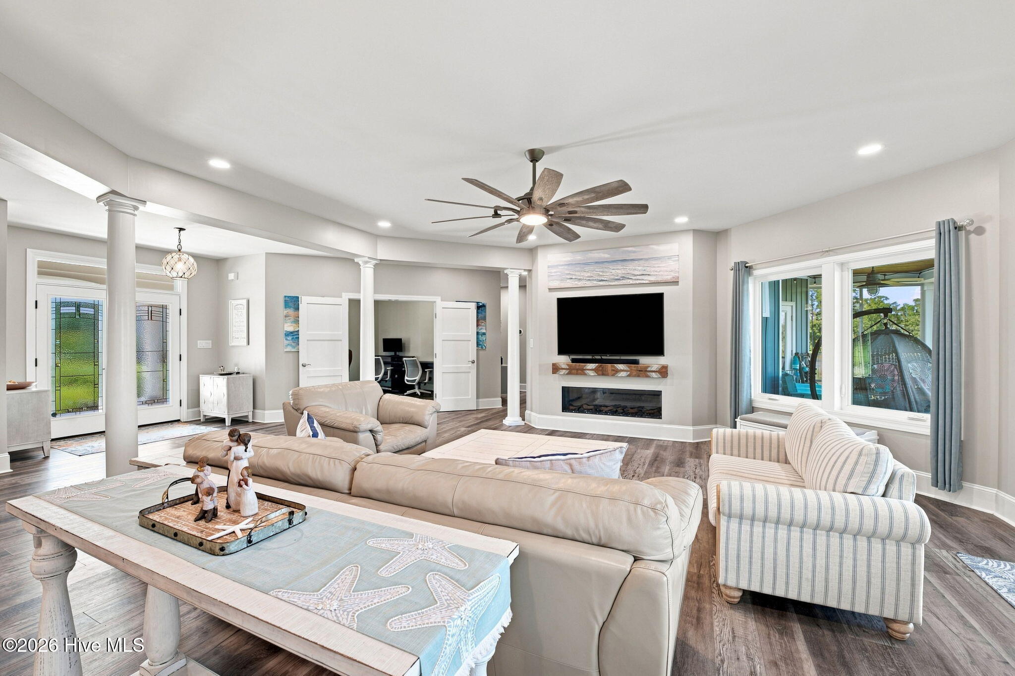 Living room with a fireplace, white columns, and a window overlooking a covered porch.