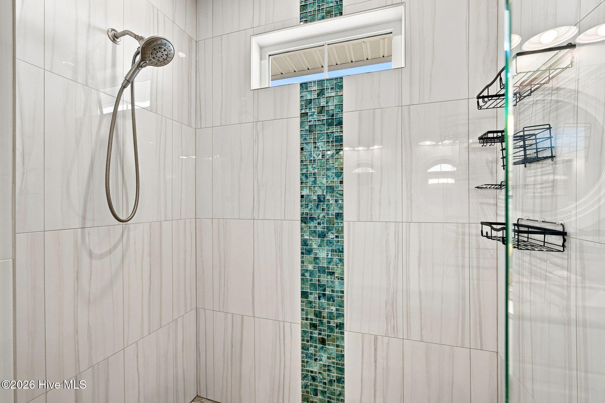 Walk-in shower with teal mosaic tile accent, handheld showerhead, and black wire caddies.