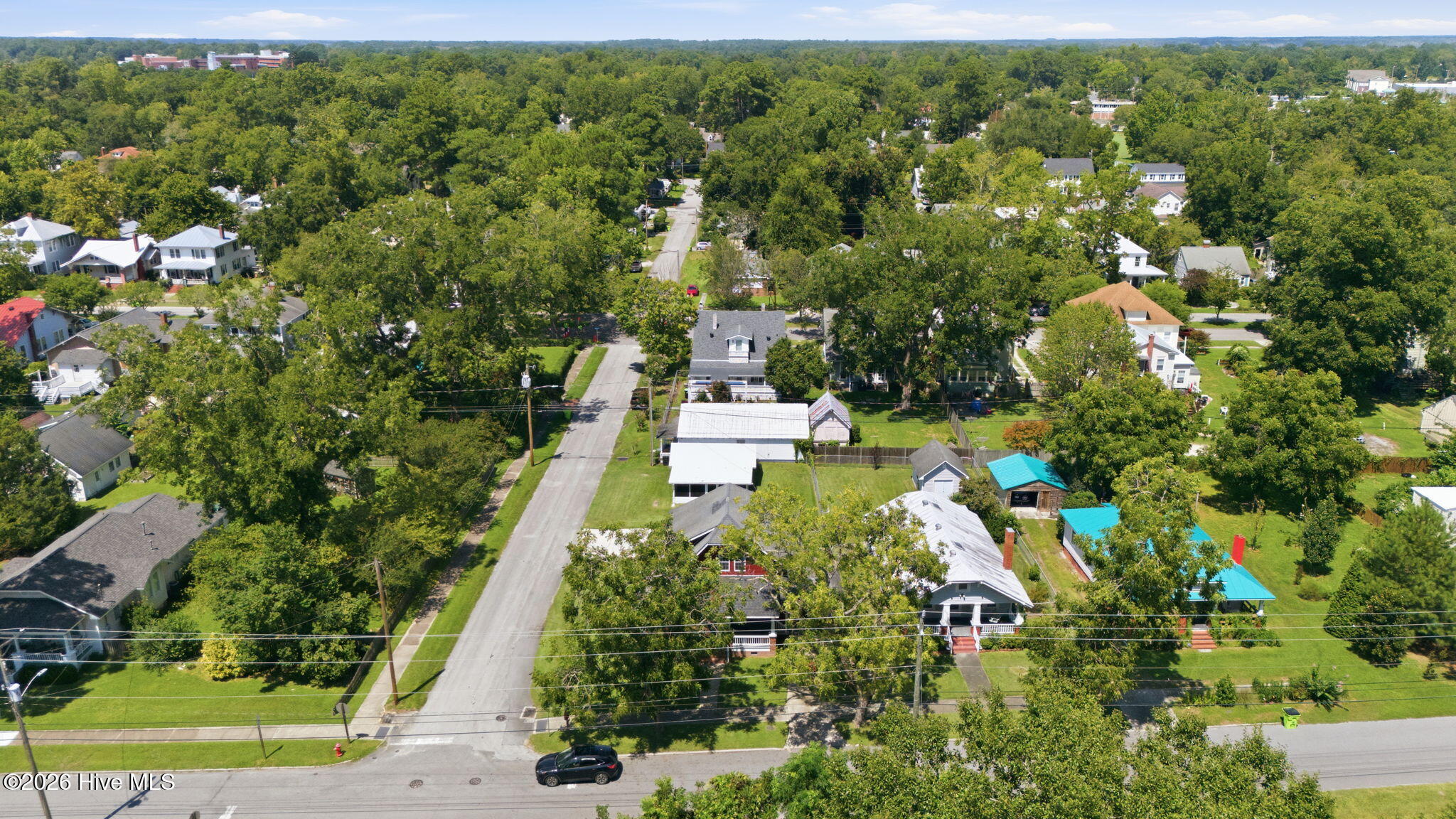 Aerial view of a tree-lined residential street and surrounding homes.