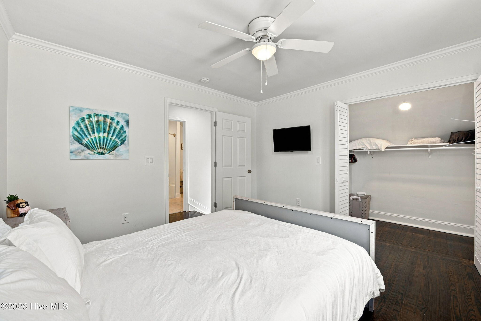 Bedroom with a large white bed, dark wood floors, and an open closet.